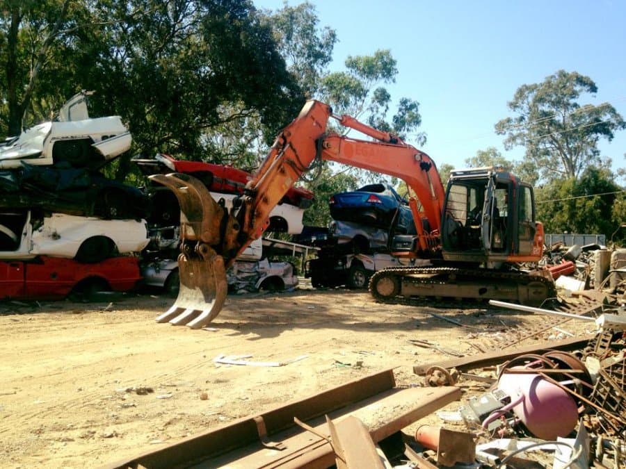 Excavator claw sorting scrap cars and metal at the FSM yard